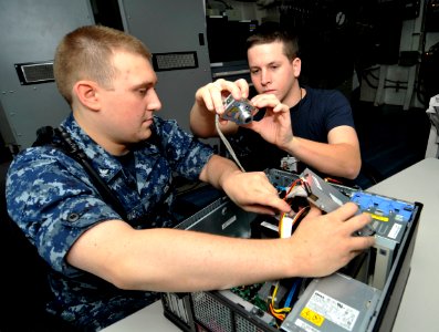 US Navy 100626-N-6003P-040 Information Systems Technicians 3rd Class Travis Golding and Michael Wentz take photographs for a manual on how to assemble computer towers
