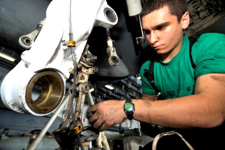 US Navy 100624-N-6003P-092 Aviation Structural Mechanic 3rd Class Donald Elder replaces an axle lever on the landing gear of an F-A-18C Hornet aboard the aircraft carrier USS Harry S. Truman (CVN 75)