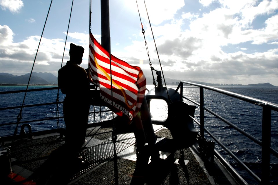 US Navy 100624-N-6477M-362 Aviation Boatswain's Mate (Fuel) Airman William Harcourt raises the Navy Jack aboard the amphibious transport dock ship USS Cleveland (LPD 7) after the ship drops anchor