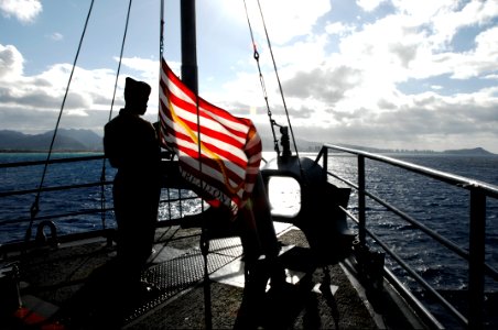 US Navy 100624-N-6477M-362 Aviation Boatswain's Mate (Fuel) Airman William Harcourt raises the Navy Jack aboard the amphibious transport dock ship USS Cleveland (LPD 7) after the ship drops anchor