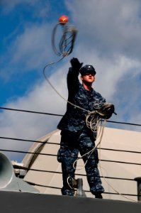US Navy 100624-N-6674H-011 A Sailor aboard the littoral combat ship USS Freedom (LCS 1) throws a line to the pier as the ship arrives at Joint Base Pearl Harbor-Hickam for Rim of the Pacific (RIMPAC) 2010 photo