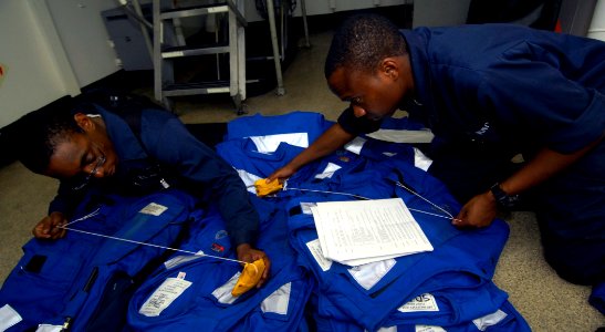 US Navy 100628-N-4135M-118 Boatswain's Mate Seaman Apprentice Toy Hudson and Boatswain's Mate Seaman Christopher Jerry perform preventative maintenance on MK-1 life preserver vests