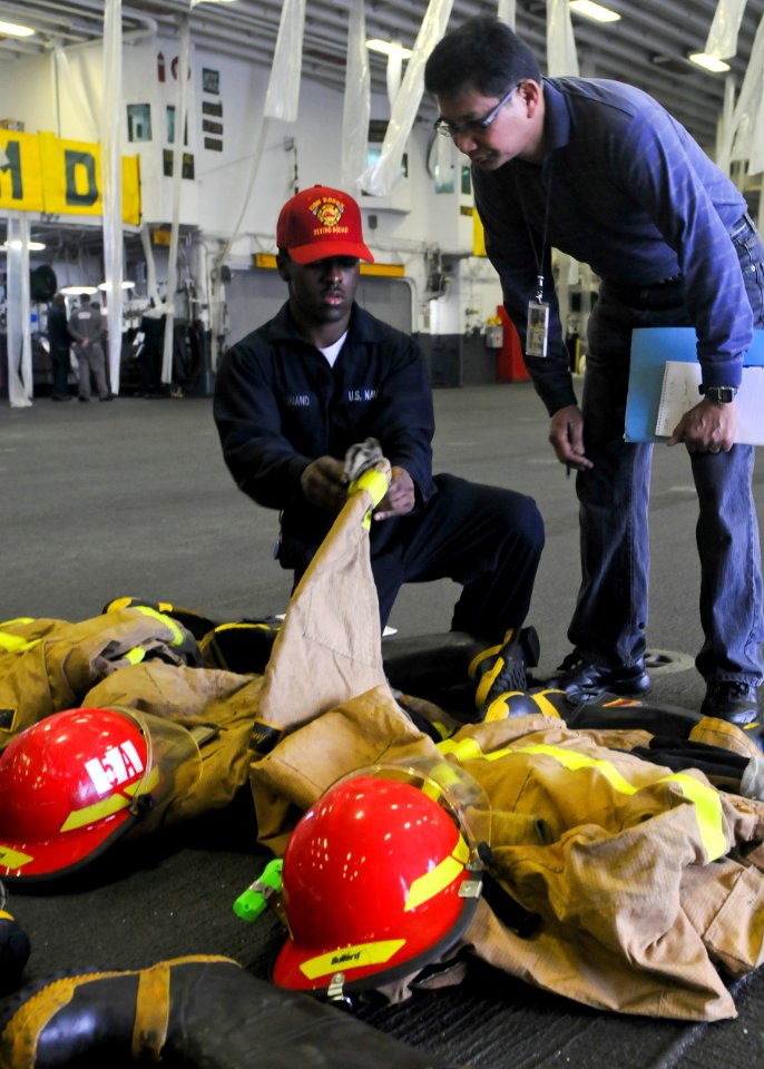 US Navy 100628-N-9950J-067 Damage Controlman Fireman Mitch Ferdinand presents firefighting ensembles to an inspector during Inspection and Survey aboard the forward-deployed amphibious assault ship USS Essex (LHD 2)