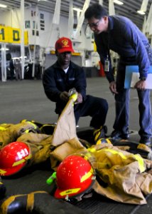 US Navy 100628-N-9950J-067 Damage Controlman Fireman Mitch Ferdinand presents firefighting ensembles to an inspector during Inspection and Survey aboard the forward-deployed amphibious assault ship USS Essex (LHD 2)