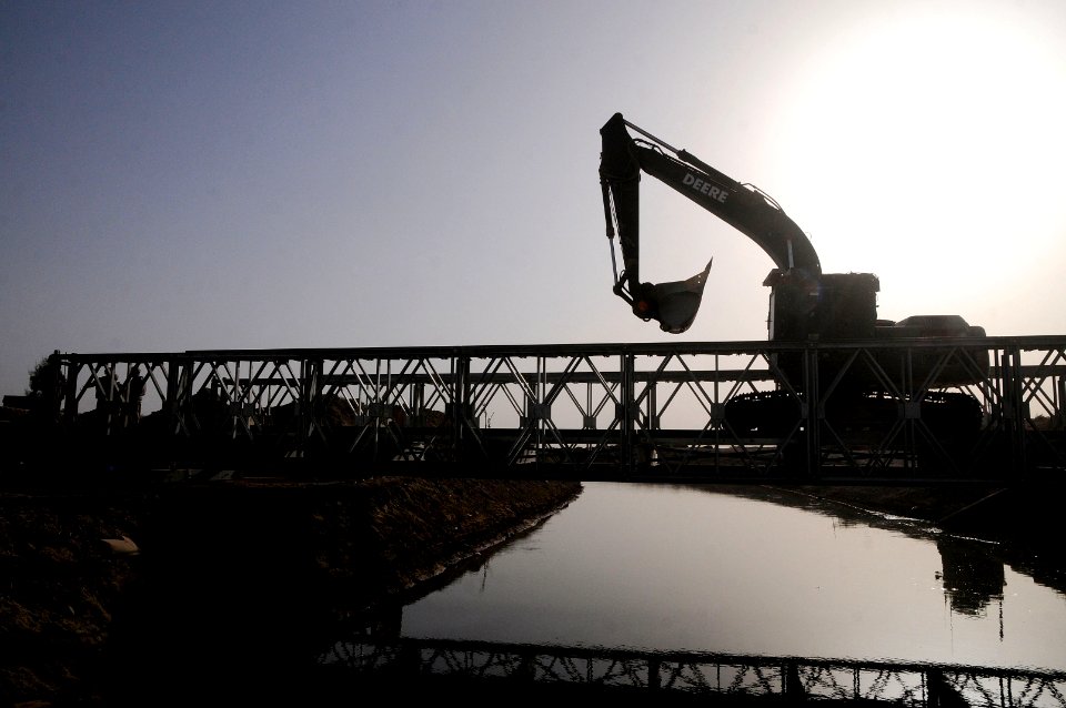 US Navy 100628-N-0475R-094 quipment Operator Constructionman Julie Watkins, assigned to Naval Mobile Construction Battalion (NMCB) 5, drives an excavator over a newly finished Mabey-Johnson Bridge