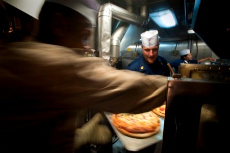 US Navy 100626-N-5319A-022 Chief Yeoman Chris Sherman assigned to Amphibious Squadron (PHIBRON) 5, removes a tray of pizzas from the oven