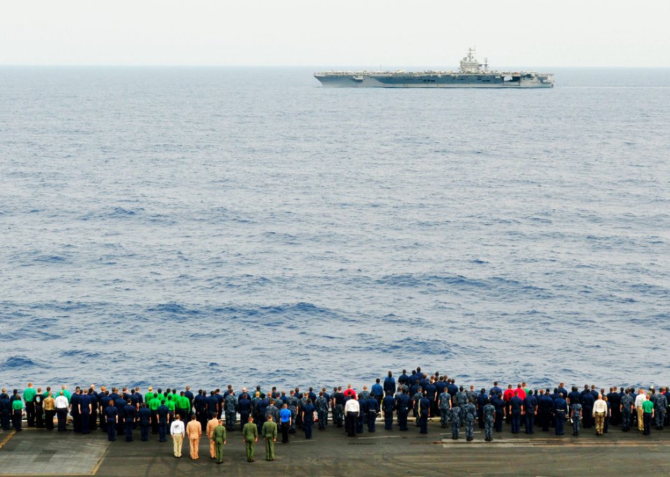 US Navy 100626-N-3595W-005 Sailors aboard the aircraft carrier USS Dwight D. Eisenhower (CVN 69) stand at attention on the flight deck as the aircraft carrier USS Harry S. Truman (CVN 75) transits past