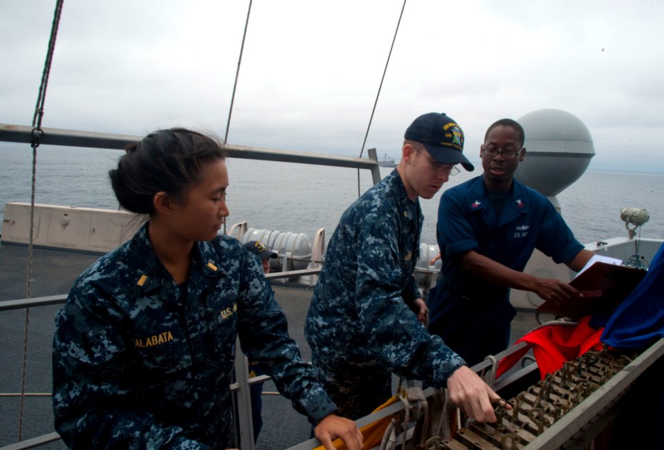 US Navy 100701-N-5319A-030 Quartermaster 1st Class Martez Smith instructs Ensigns Jessica Alabata and Andrew Norris how to raise signal flags during flag signaling drills