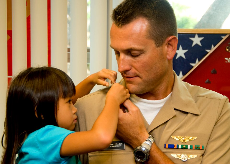 US Navy 100701-N-5476H-001 The daughter of Lt. Cmdr. Terry Fellows pins a new collar device on her father's uniform during a promotion ceremony at Commander, U.S. Pacific Fleet Headquarters