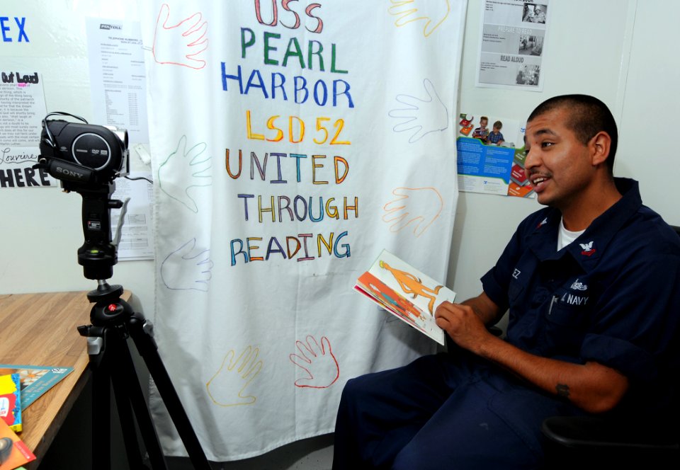 US Navy 100706-N-7948R-017 Quartermaster 2nd Class Abraham Velez, from Los Angeles, is videotaped reading a book to his children aboard the amphibious dock landing ship USS Pearl Harbor (LSD 52)