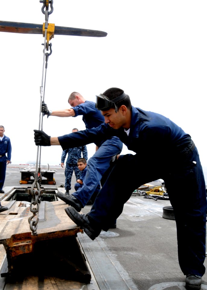 US Navy 100702-N-3327M-012 Aviation Boatswain's Mate (Equipment) Airman Milton Arevalo and Aviation Boatswain's Mate (Equipment) 3rd Class Aaron Patterson emoves a catapult deck-plate prior to maintenance