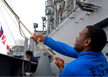 US Navy 100702-N-4830B-065 Aviation Boatswains Mate (Handling) Airman Apprentice Eddie Martin, from Atlanta, heaves an up and over line for decorating aircraft carrier USS George Washington (CVN 73) for the ship's 4th of July c