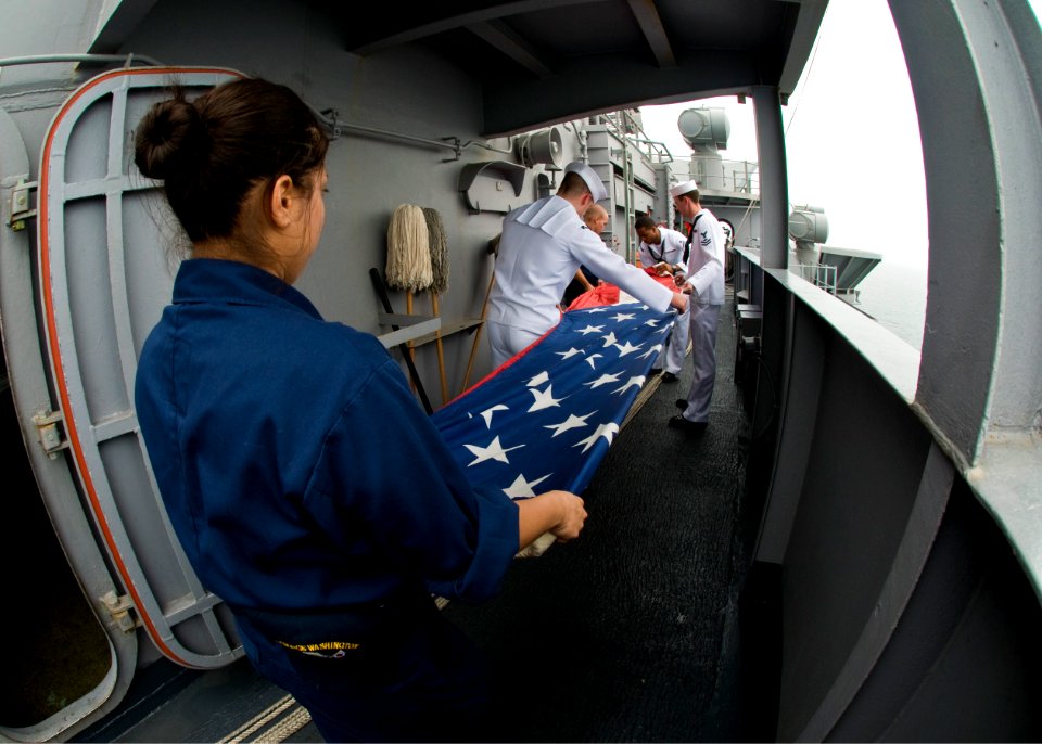 US Navy 100702-N-4830B-094 Sailors aboard the aircraft carrier USS George Washington (CVN 73) fold the national ensign to ready it for the shifting of colors as the ship pulls into port