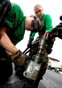 US Navy 100703-N-7191M-038 Aviation Boatswain's Mate (Equipment) Airman Kyle Smith, left, from Clarksville, Tenn., de-torques the arresting gear purchase cable on the flight deck aboard the aircraft carrier USS George Washingto