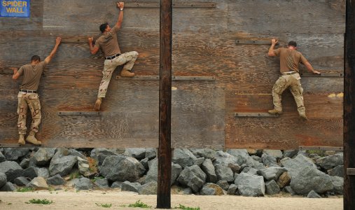 US Navy 100708-N-0775Y-106 Sailors ssigned to Fleet Combat Camera Group Pacific, crawl across narrow planks of wood to navigate the Spider Wall portion of the obstacle course photo