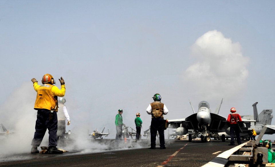 US Navy 100704-N-6003P-032 A plane director guides an F-A-18 Hornet onto the catapult for take-off aboard the aircraft carrier USS Harry S. Truman (CVN 75)