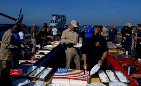 US Navy 100704-N-9706M-126 Capt. Christopher Bolt, commanding officer of the amphibious transport dock ship USS Dubuque (LPD 8), enjoys a piece of cake while Command Master Chief Reinaldo Rosado cuts the cake photo