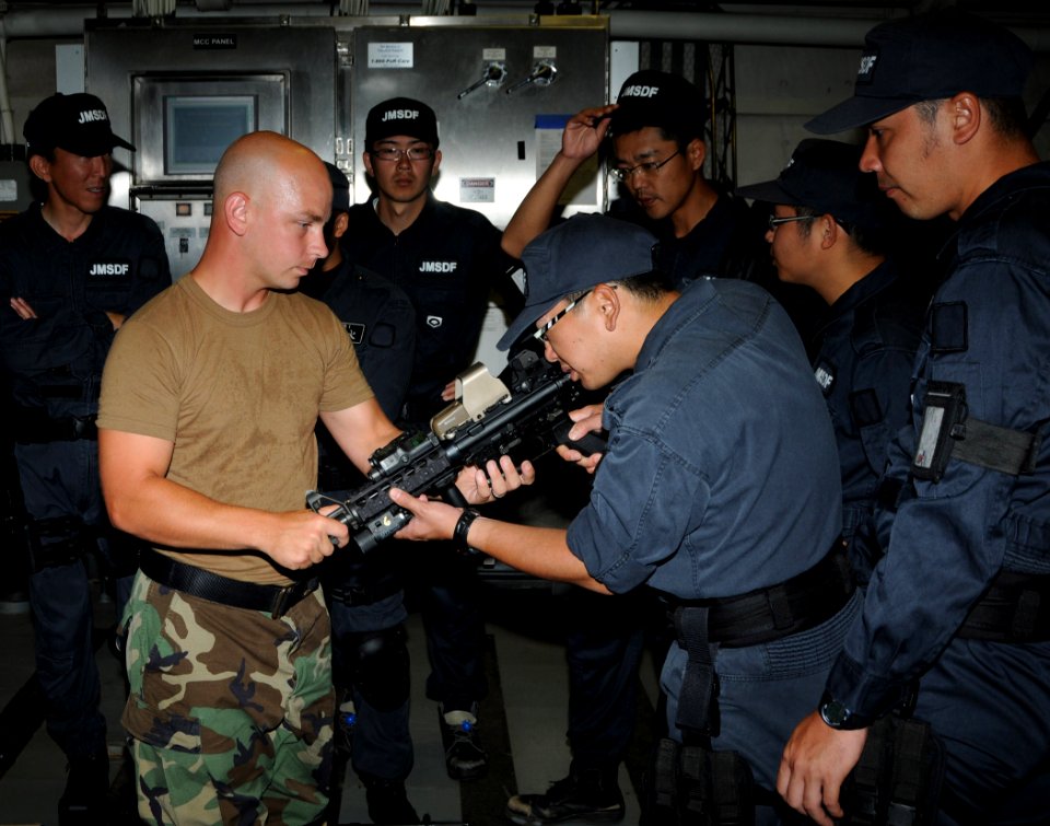 US Navy 100705-N-7058E-054 Hull Maintenance Technician 1st Class Keith Vanbuskirk demonstrates the sighting system for an M4 assault rifle to a Japan Maritime Self-Defense Force sailor