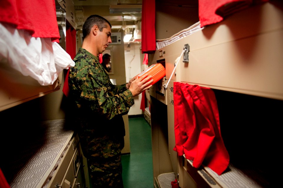 US Navy 100709-N-5319A-057 Peruvian Lt. Col. Renzo Corvetto looks at an emergency escape breathing device while touring a berthing space aboard aboard USS New Orleans (LPD 18)