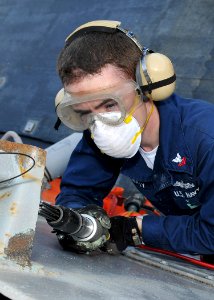 US Navy 100708-N-2013O-011 Electronics Technician 2nd Class Brian McNulty, from Binghamton, N.Y., uses a needle gun to remove paint from a life rail support during ship preservation efforts