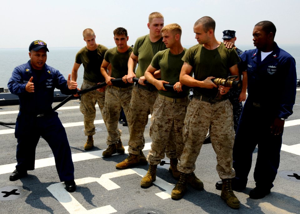 US Navy 100707-N-3154P-037 Aviation Boatswain's Mate 1st Class Jesse Seagrave and Aviation Boatswain's Mate Victor Perry teach Marines the proper way to handle a hose during an aviation fire drill