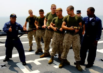 US Navy 100707-N-3154P-037 Aviation Boatswain's Mate 1st Class Jesse Seagrave and Aviation Boatswain's Mate Victor Perry teach Marines the proper way to handle a hose during an aviation fire drill