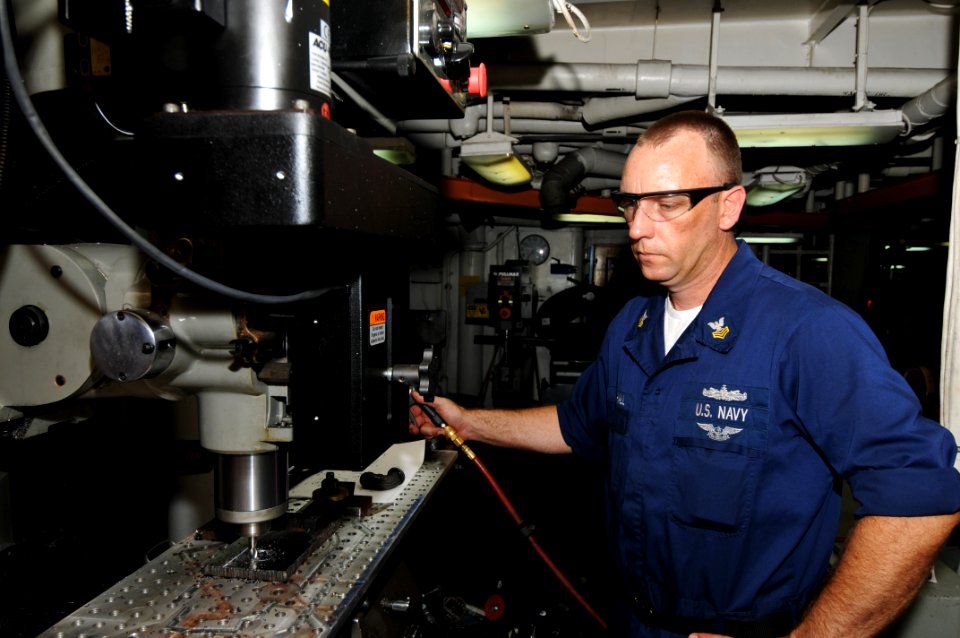 US Navy 100707-N-6362C-008 Machinery Repairman 1st Class Aaron Marshall uses a computer numerical control lathe to create brackets for water sink fittings in the machine shop aboard the aircraft carrier USS Harry S. Truman (CVN