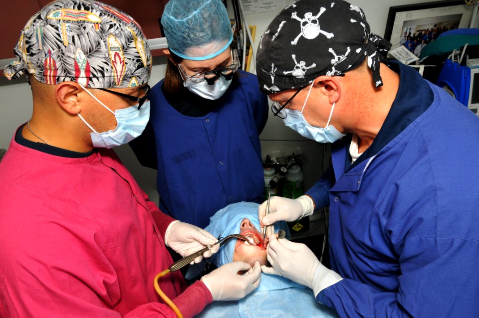 US Navy 100707-N-6362C-047 Capt. Zachary J. Berry, right, Lt. Amy Respondek and Hospital Corpsman 3rd Class Enrique Leytividal perform a multiple wisdom tooth extraction
