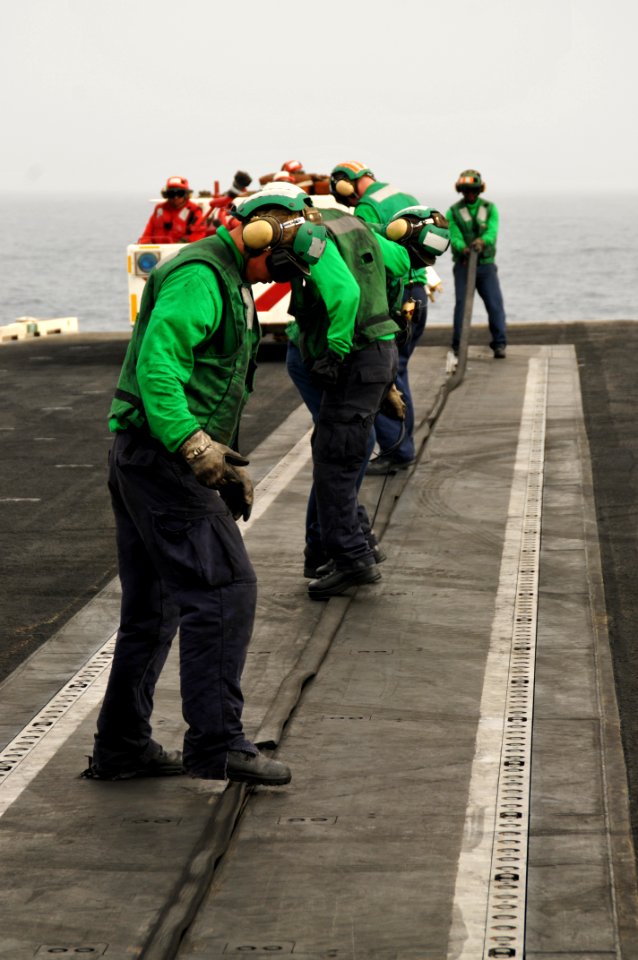 US Navy 100707-N-6362C-256 Sailors assigned to the arresting gear and catapults crew place a rubber gasket in the catapult track to protect it from damage and debris aboard the aircraft carrier USS Harry S. Truman (CVN 75)