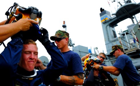 US Navy 100712-N-9769P-467 Navy Divers 1st Class Joel Sharp and Dean Bates, both assigned to Mobile Diving and Salvage Unit (MDSU) 2, don the Kirby Morgan 37 diving helmet during a mixed-gas dive from the Military Sealift Comma