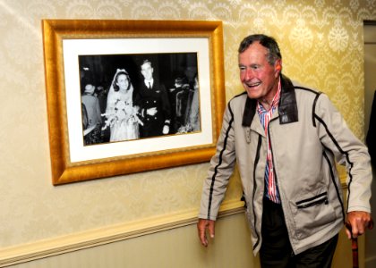 US Navy 100714-N-6632S-060 Former President George H.W. Bush walks past a portrait of himself and his wife, Barbara, in the captain's in port cabin aboard the aircraft carrier USS George H.W. Bush (CVN 77)