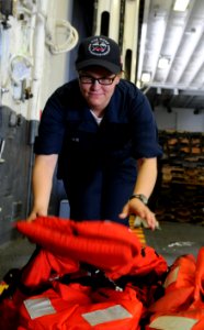 US Navy 100712-N-3852A-214 Boatswain's Mate Seaman Amber Seger assigned to the amphibious assault ship USS Wasp (LHD1) organizes life jackets while the ship gets underway