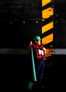 US Navy 100713-N-2908M-009 A sailor aboard the amphibious assault ship USS Kearsarge (LHD 3) stands by during the approach of a small craft into the ship's well deck photo