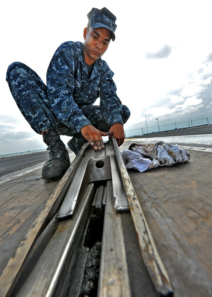US Navy 100714-N-5082P-019 Aviation Boatswain's Mate (Equipment) Airman Anthony E. Blanchfield performs pre-operation maintenance on the shuttle and spread component of catapult one aboard the aircraft carrier USS Enterprise (C