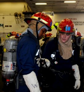 US Navy 100719-N-3852A-127 Electrician's Mate Fireman Brian Young, right, checks Electrician's Mate Fireman Marion Tillis' mask before a toxic gas drill