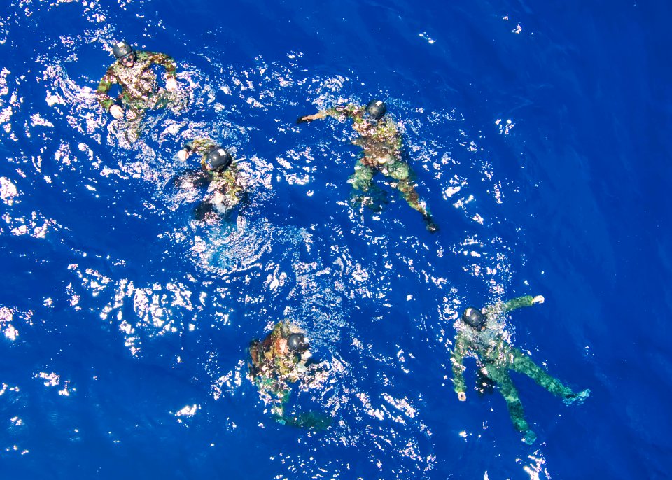 US Navy 100719-N-6720T-130 Explosive Ordnance Disposal Technicians tread water while waiting to be hoisted by an HH-60H Sea Hawk helicopter during cast and recovery training