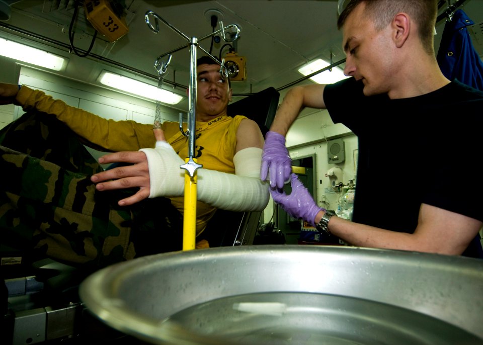 US Navy 100720-N-4830B-010 Hospital Corpsman 3rd Class Joseph Grabianowski wraps fiberglass casting tape on Aviation Boatswain's Mate (Handling) Airman Ronald Lewis after he fractured his arm during a fall