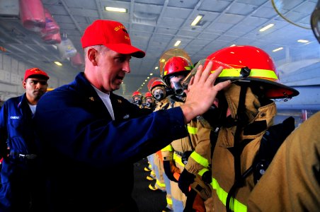 US Navy 100717-N-2953W-762 Senior Chief Damage Controlman Michael Bates adjusts a hose team member's firefighting equipment after simulated firefighting efforts aboard USS Carl Vinson (CVN 70)