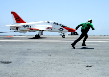 US Navy 100717-N-6632S-328 An air department Sailor runs with a T-45C Goshawk training aircraft assigned to Training Wing (TRAWING) 2 as it lands aboard the aircraft carrier USS George H.W. Bush (CVN 77)