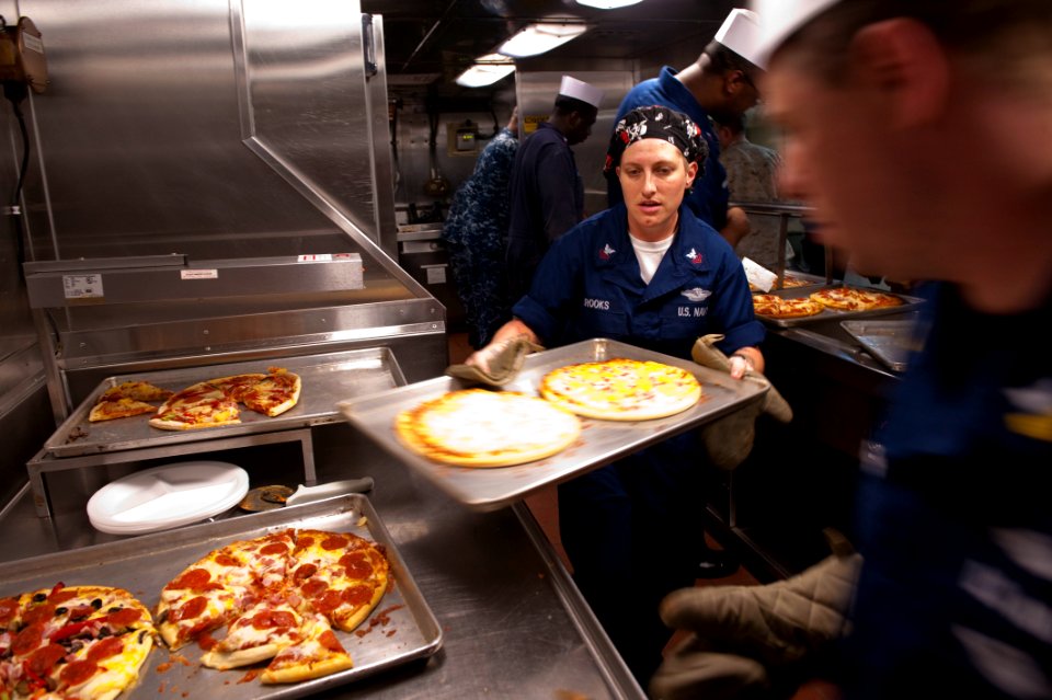 US Navy 100717-N-5319A-028 Hospital Corpsman 1st Class Erin Brooks prepares pizzas as the Navy and Marine Corps E-6 community aboard USS New Orleans (LPD 18) take over galley duties for dinner