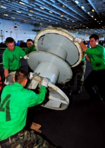 US Navy 100718-N-0569K-126 Sailors assigned to the Air department of the aircraft carrier USS Enterprise (CVN 65) move a spool that holds the number two arresting gear wire