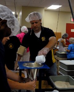 US Navy 100719-N-2389S-009 Senior Chief Gunner's Mate Casey Carlson, assigned to Navy Recruiting District Minneapolis, fills bags with rice for the Feed My Starving Children organization as part of Twin Cities Navy Week
