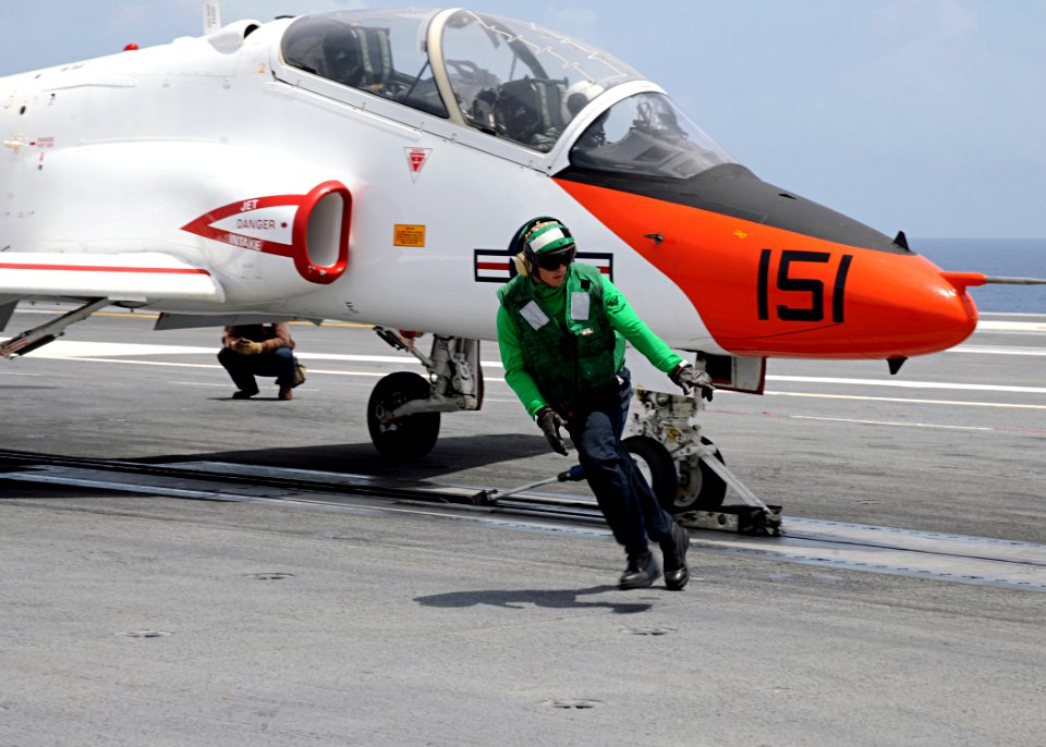 US Navy 100719-N-3885H-090 A Sailor assigned to the air department of the aircraft carrier USS George H.W. Bush (CVN 77) runs to the foul line as a T-45C Goshawk training aircraft assigned to Training Wing (TRAWING) 1 prepares