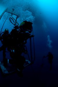 US Navy 100722-N-1134I-172 Navy Diver 2nd Class Troy Crowder ooks over the edge of a dive platform to make sure the platform has a clear landing area on the ocean floor