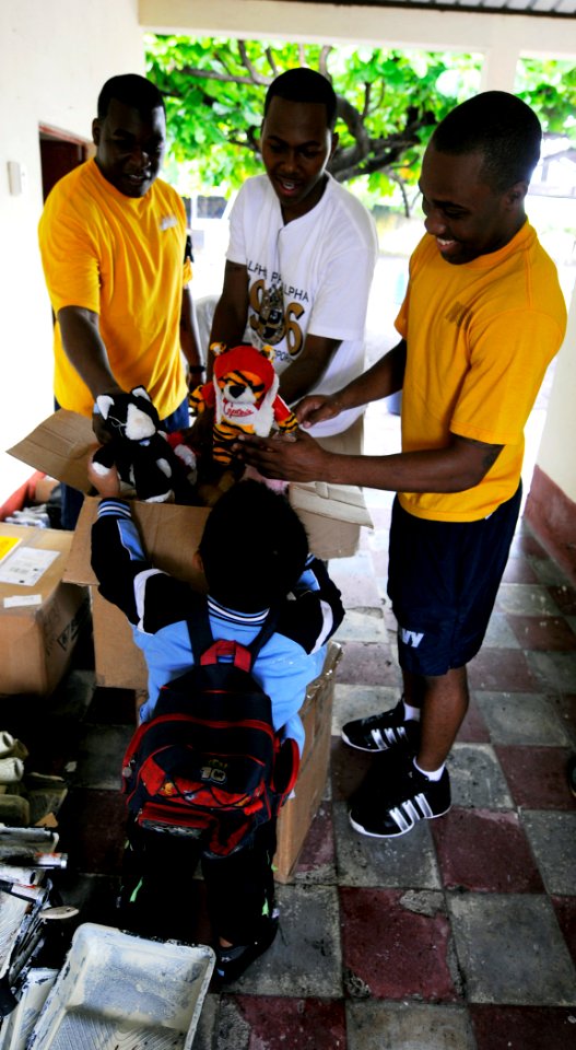US Navy 100719-N-9643W-189 Yeoman 1st Class Raymond Jenkins, Logistics Specialist 1st Class Eric Jones and Seaman Adam Rogers give stuffed toys to a student from Escuela De Las Pampas during a community relations event