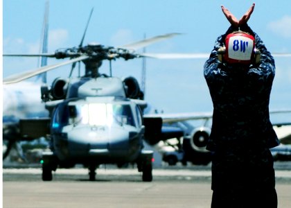 US Navy 100720-N-6854D-049 Aviation Ordnanceman Airman Mario Trejo signals the pilot of an MH-60S Sea Hawk helicopter