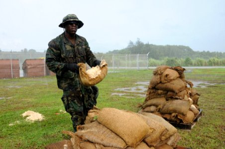 US Navy 100723-N-1906L-005 Master-at-Arms 2nd Class Jabril Muhammad, assigned to Maritime Expeditionary Security Squadron (MSRON) 7, moves sandbags to fortify an emplacement photo