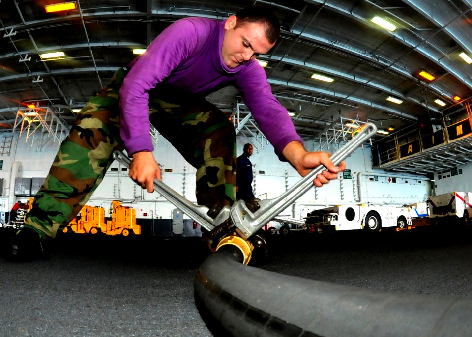US Navy 100721-N-0569K-096 Aviation Boatswain's Mate (Fuel) Airman Michael A. Genera switches a nozzle to make it more compatible with a different hose aboard USS Enterprise (CVN 65)