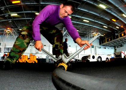 US Navy 100721-N-0569K-096 Aviation Boatswain's Mate (Fuel) Airman Michael A. Genera switches a nozzle to make it more compatible with a different hose aboard USS Enterprise (CVN 65)