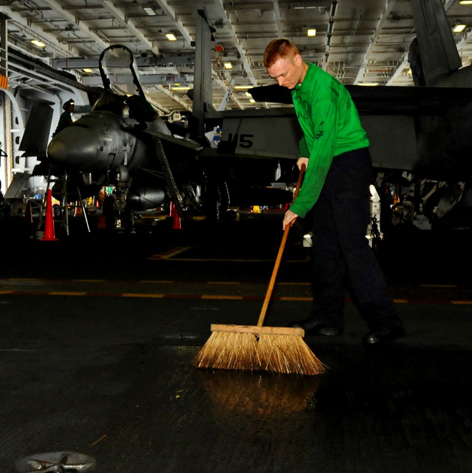 US Navy 100721-N-1092P-047 Aviation Machinist's Mate 2nd Class Robert Inwood cleans up fuel and hydraulic fluid in the hangar bay of USS Harry S. Truman (CVN 75)